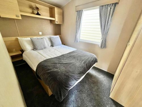 a small bedroom with a bed and a window at california cliffs caravan 2 dunlin in Scratby