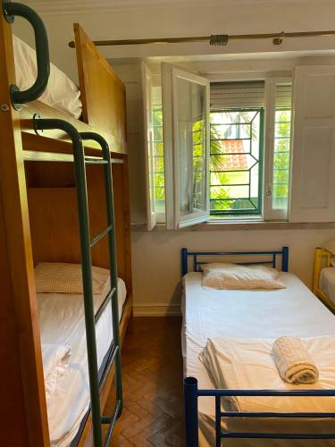 two bunk beds in a room with two windows at Botanique Guesthouse in Cascais