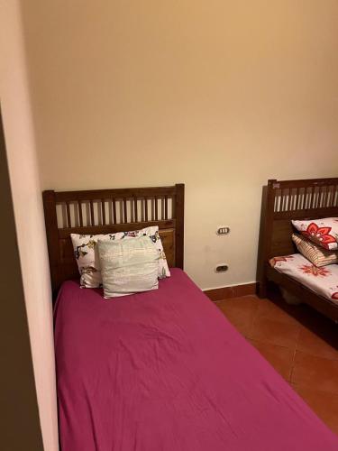 a bedroom with a bed with purple sheets and pillows at Cozy chalet in El Alamein