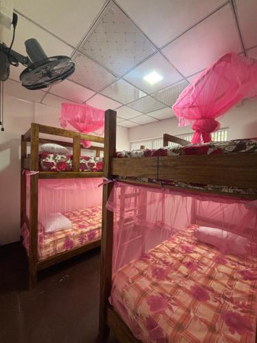 two bunk beds in a room with pink sheets at Lake Hostel Anuradhapura in Anuradhapura