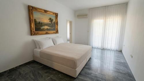 a bedroom with a bed with a painting on the wall at Kineta Prime Suites No6 in Kineta