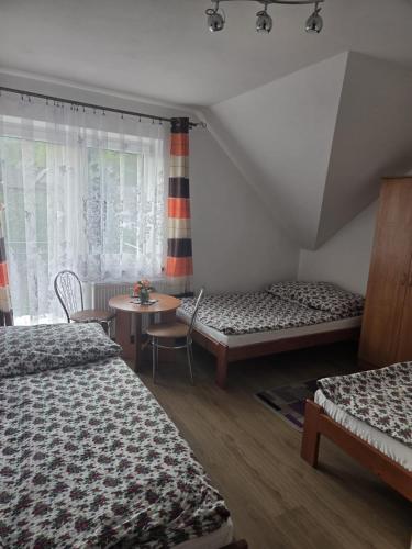 a bedroom with two beds and a table and a window at Gościnne Pieniny Pensjonat in Jaworki