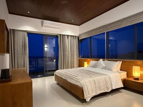 a bedroom with a large bed and large windows at Oceana Trinco in Trincomalee
