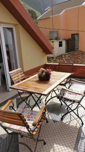 a wooden table with a bowl of flowers on a patio at Casa da Guida in Paul do Mar