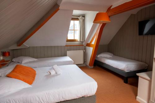 a attic room with two beds and a tv at Logis - Hotel & Restaurant La Corne d 'Abondance in Bourgthéroulde