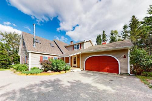 a white house with a red garage at Dog-friendly, bayfront home w/rocky beach, full kitchen, washer/dryer & firepit in Gouldsboro