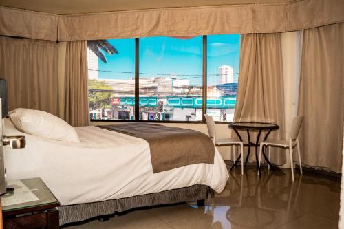 a bedroom with a bed and a large window at Hotel Cano in Iquique