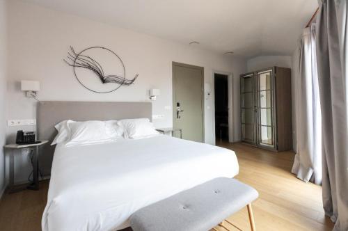 a bedroom with a large white bed and a chair at Posada Sillería - Historic boutique Hotel in Toledo