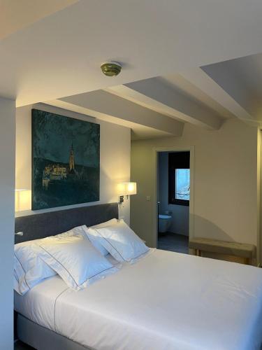 a bedroom with a white bed with a painting on the wall at Posada Sillería - Historic boutique Hotel in Toledo