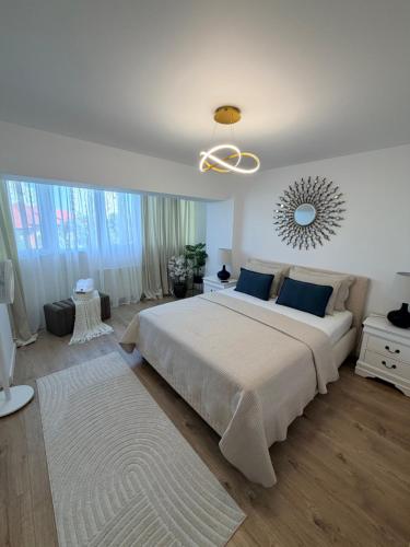 a white bedroom with a large bed and a chandelier at Urban Central Hub in Giurgiu