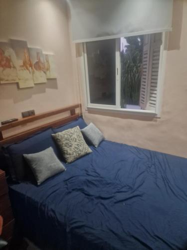 a bedroom with a blue bed with pillows and a window at apparemment wifaq in Temara