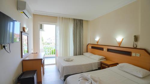 a hotel room with two beds and a window at Side Özgürhan Hotel in Side