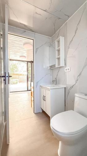 a white bathroom with a toilet and a sink at Chalet met grote tuin en privé jacuzzi in Wijdenes