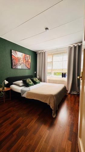 a bedroom with a large bed in a green wall at Light and Spacious Getaway House in Arnhem