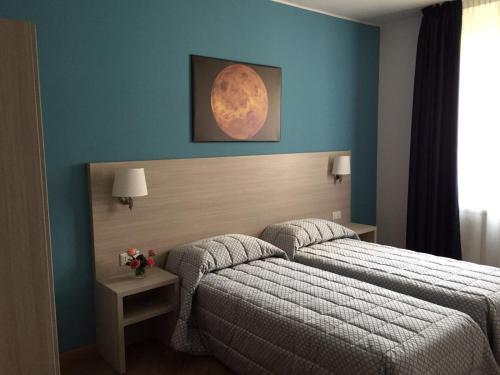 a bedroom with two beds and a moon painting on the wall at Spazio Gran Paradiso Guest House in Alpette
