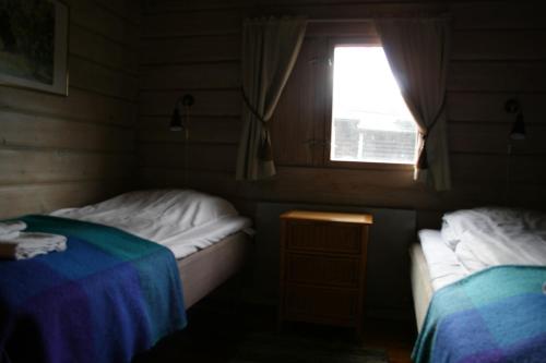 two beds in a small room with a window at Tallhöjden Hotel & Cottage Lodge in Simlångsdalen