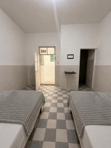 two beds in a room with a checkered floor at Los Olivos in Atlixco