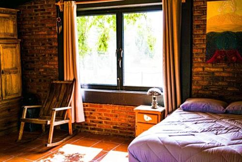 a bedroom with a bed and a chair and a window at Lovely garden flat with stunning mountain views in Alcocer