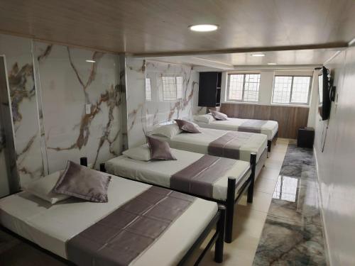 a group of three beds in a room at Hotel La Castellana in Manizales