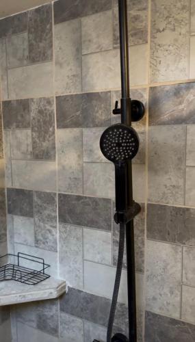 a shower in a bathroom with a stone wall at The Jungle Chalet in Cebadilla