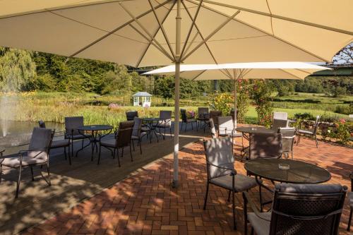 a patio with tables and chairs and an umbrella at Romantik Hotel Waldschlösschen in Schleswig