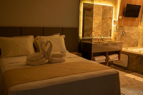 a bedroom with a bed with towels and a sink at Hotel Entre Rios in Pontalina