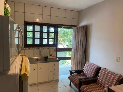 a kitchen with a sink and two chairs in a room at GH Pinheira in Palhoça