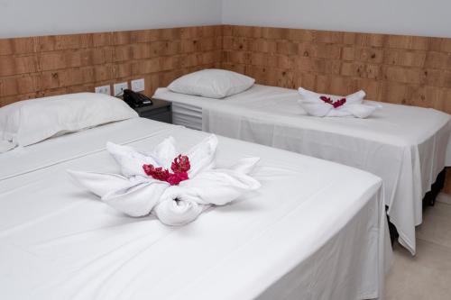 two white beds with flowers on top of them at Hotel Entre Rios in Pontalina