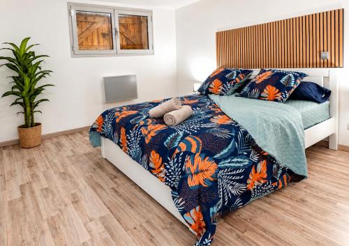 a bedroom with a bed with a blue and orange blanket at ''Le Nid du Forez'' appartement 2 chambres , parking gratuit ,terrasse privative in Prétieux