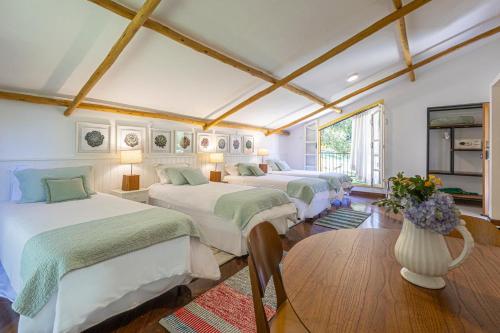 a room with four beds and a vase with flowers at Fazenda Montanhas do Japi in Jundiaí