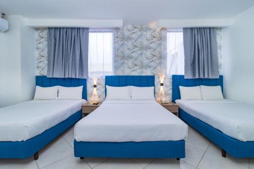 two beds in a room with two windows at Hotel Presidente Beach Salinas in Salinas