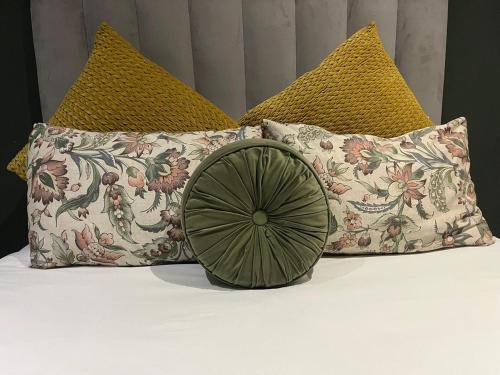 a bed with four pillows and a green bowl on it at West Coast comfortable stays in Cape Town