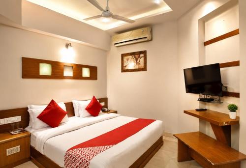 a bedroom with a bed with red pillows and a tv at HOTEL CAMPUS in Ahmedabad