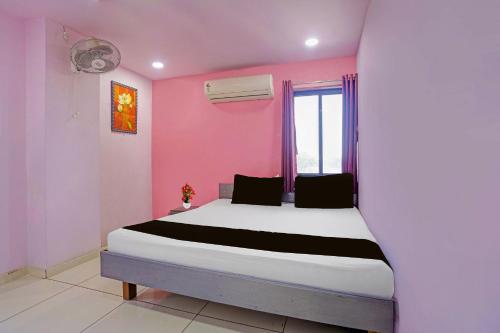 a bedroom with a bed in a pink room at Hotel O Unity Guest House in Dabhoi