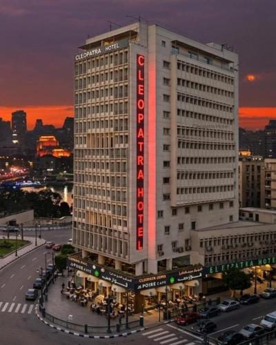 a tall white building with a red sign on it at Cleopatra Hotel in Cairo