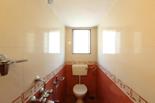 La salle de bains est pourvue de toilettes et d'une fenêtre. dans l'établissement Sea Pearl Guesthouse, à Candolim