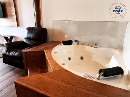 a bath tub in a room with a leather chair at Hotel Route 66 in Vichayito