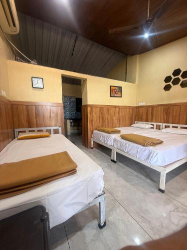 two beds in a room with wooden walls at Green Fog Guesthouse in Lonavala
