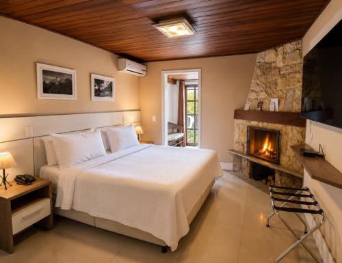 ein Schlafzimmer mit Bett und Kamin in der Unterkunft Hotel Willisau in Teresópolis