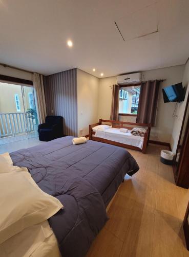 a bedroom with a large bed and a large window at Pousada Casa Hospedaria in Paraty