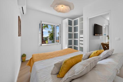 a white bedroom with a large bed with yellow pillows at B&B Villa Dubrovnik Garden in Dubrovnik