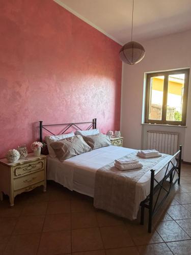 a bedroom with a bed and a pink wall at La Maison D'Amì in Anguillara Sabazia