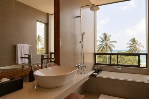 a bathroom with a tub and a sink and a window at Rekawa Reach Tangalle in Tangalle