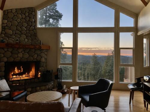 a living room with a fireplace and a large group of windows at Pinetree Palace in Lake Arrowhead