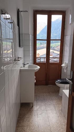a bathroom with a sink and a toilet and a window at BLACK DOLOMYTE Apartment in Schilpario