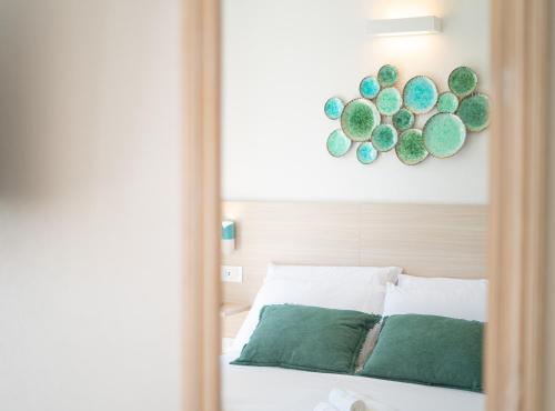 a mirror reflection of a bed with green pillows at Viver Guest House in La Caletta