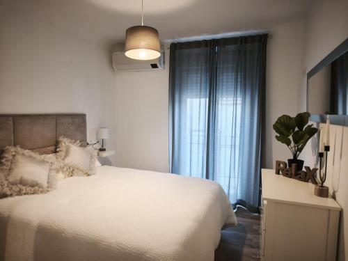 a bedroom with a white bed and a window at Los Titos in Arriate