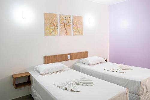 two beds in a room with white sheets at Manacá Hotel in Foz do Iguaçu