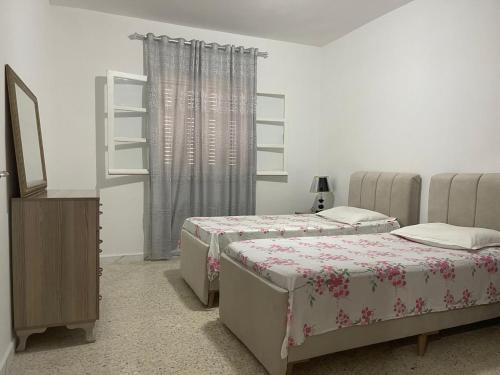 una camera da letto con due letti, un comò e una finestra di Babylon Gardens a Sousse