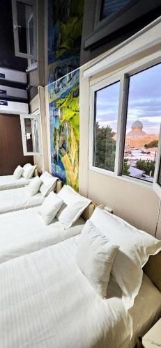 a row of white beds in a room with a window at 10 USD New Hotel in Tashkent
